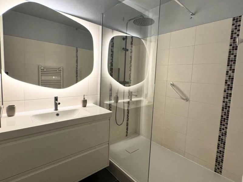 Salle de bain rénovée par NM Plomberie : douche à l'italienne, meuble-vasque et miroir rétroéclairé