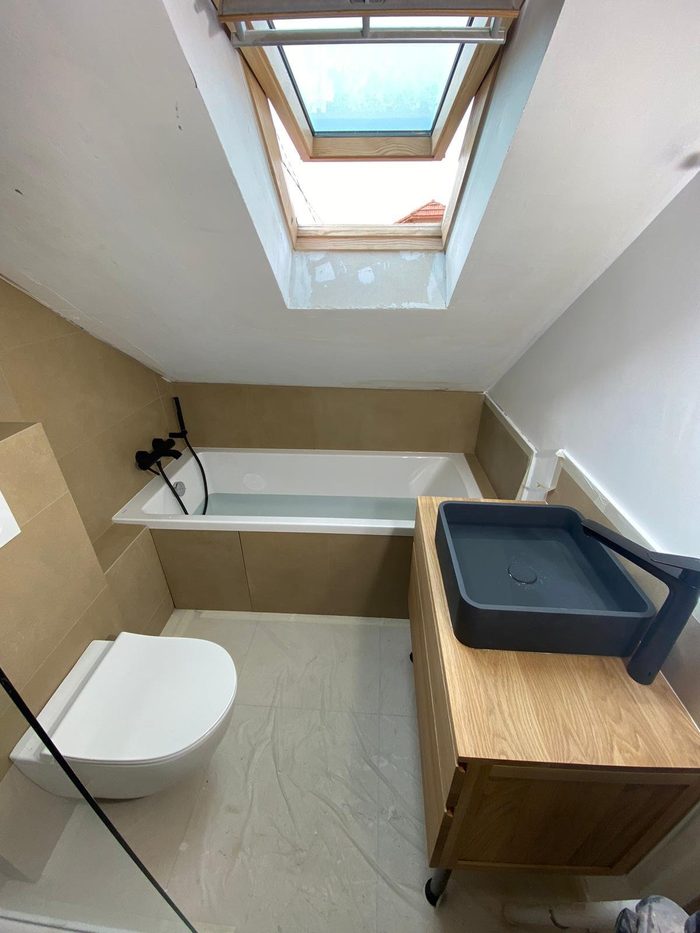 Chantier de rénovation de salle de bain en cours, baignoire et receveur protégés, sous velux