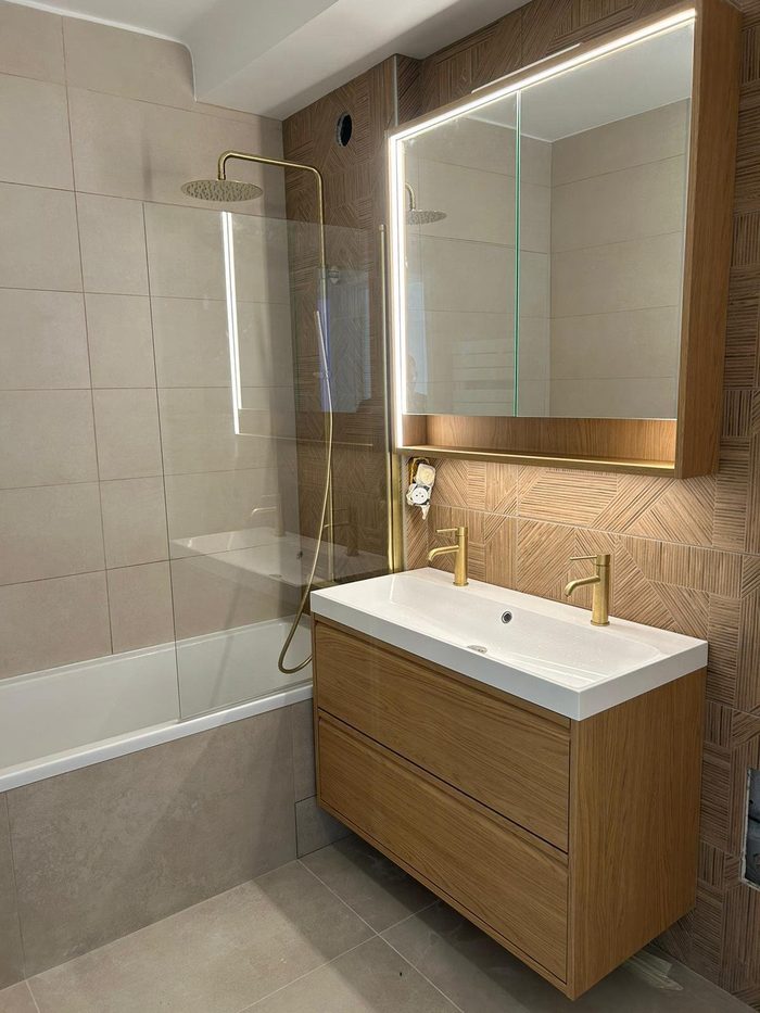 Salle de bain rénovée avec baignoire, douche vitrée et robinetterie laiton brossé