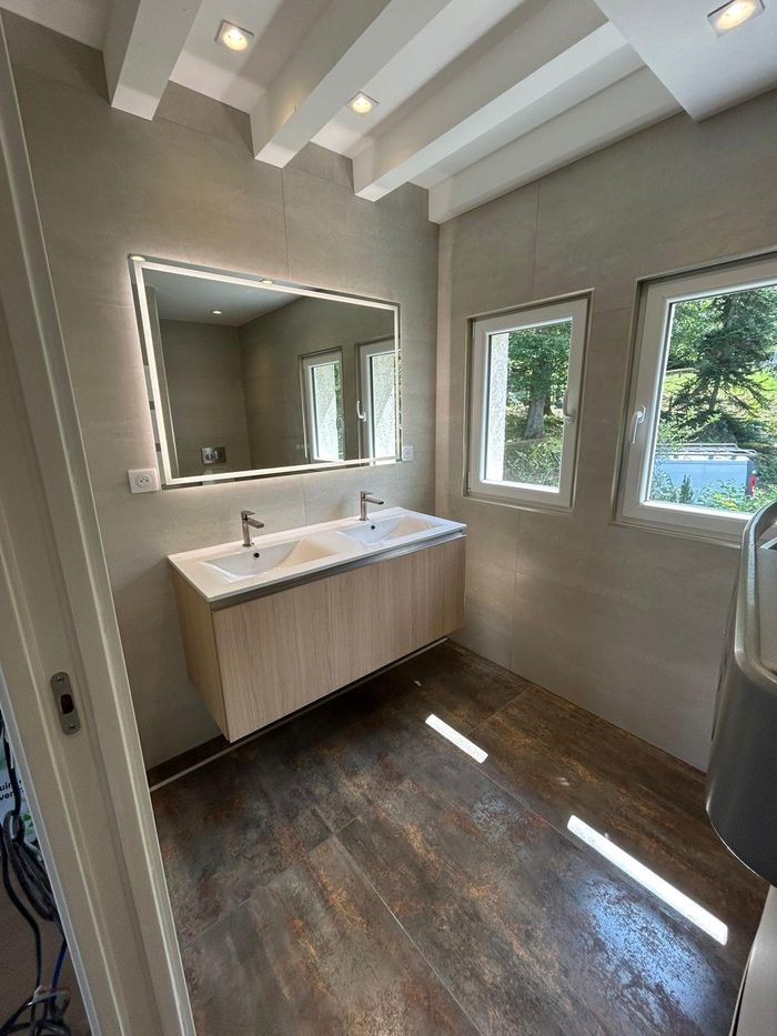 Meuble double vasque en bois clair sous grand miroir rétroéclairé