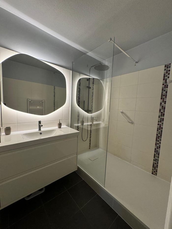 Douche vitrée avec barre d'appui, meuble vasque et miroir rétroéclairé