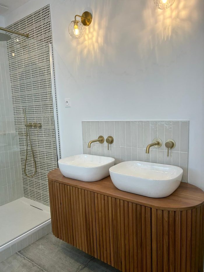 Deux vasques à poser sur meuble en bois cannelé, douche à l'italienne carrelage à motifs